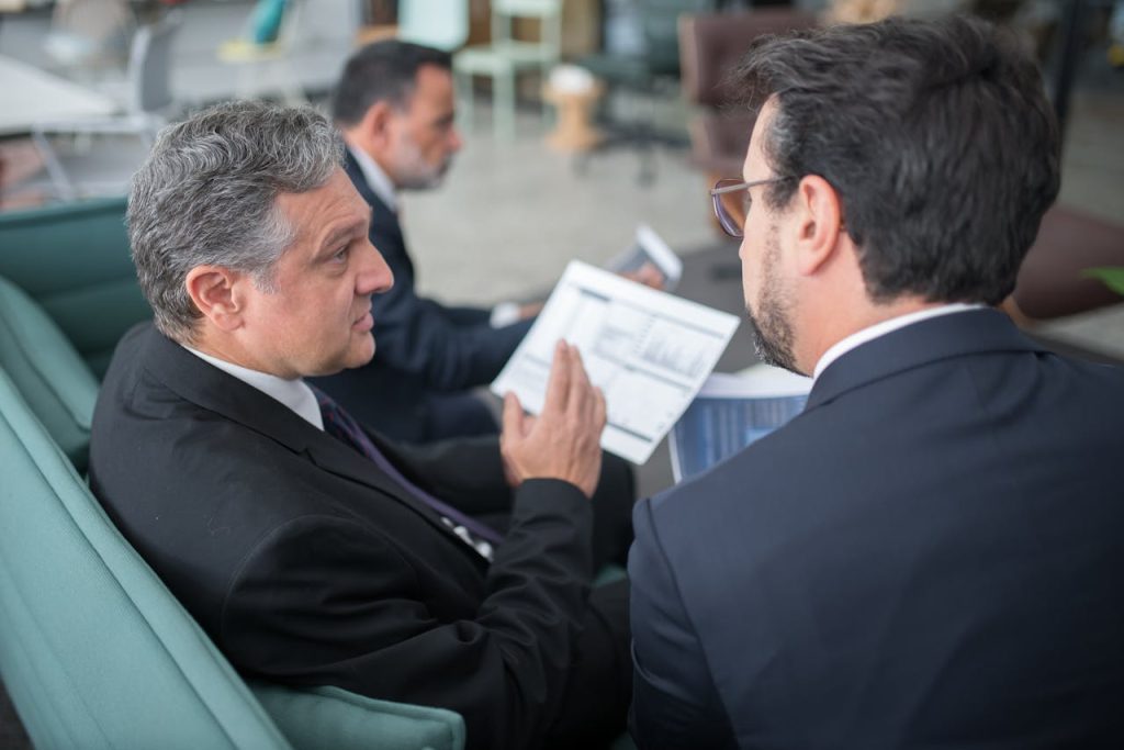 Two businessmen engaged in a discussion, examining reports in a modern office environment.